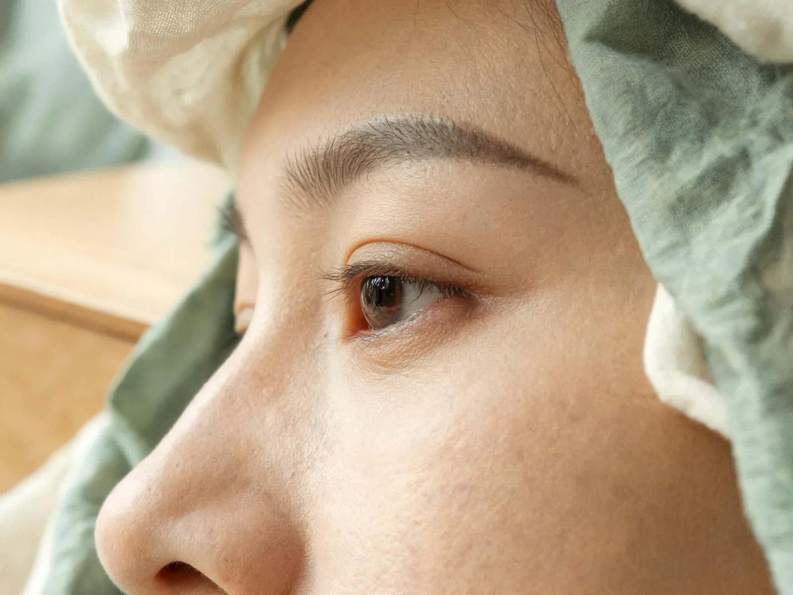 The outer eye area of a calm adult in soft daylight, natural skin.