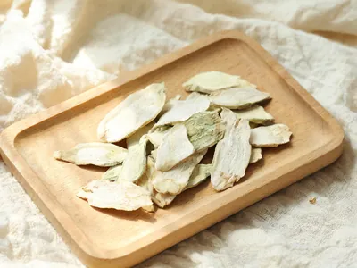 Dried bletilla tuber slices on a small wooden tray.